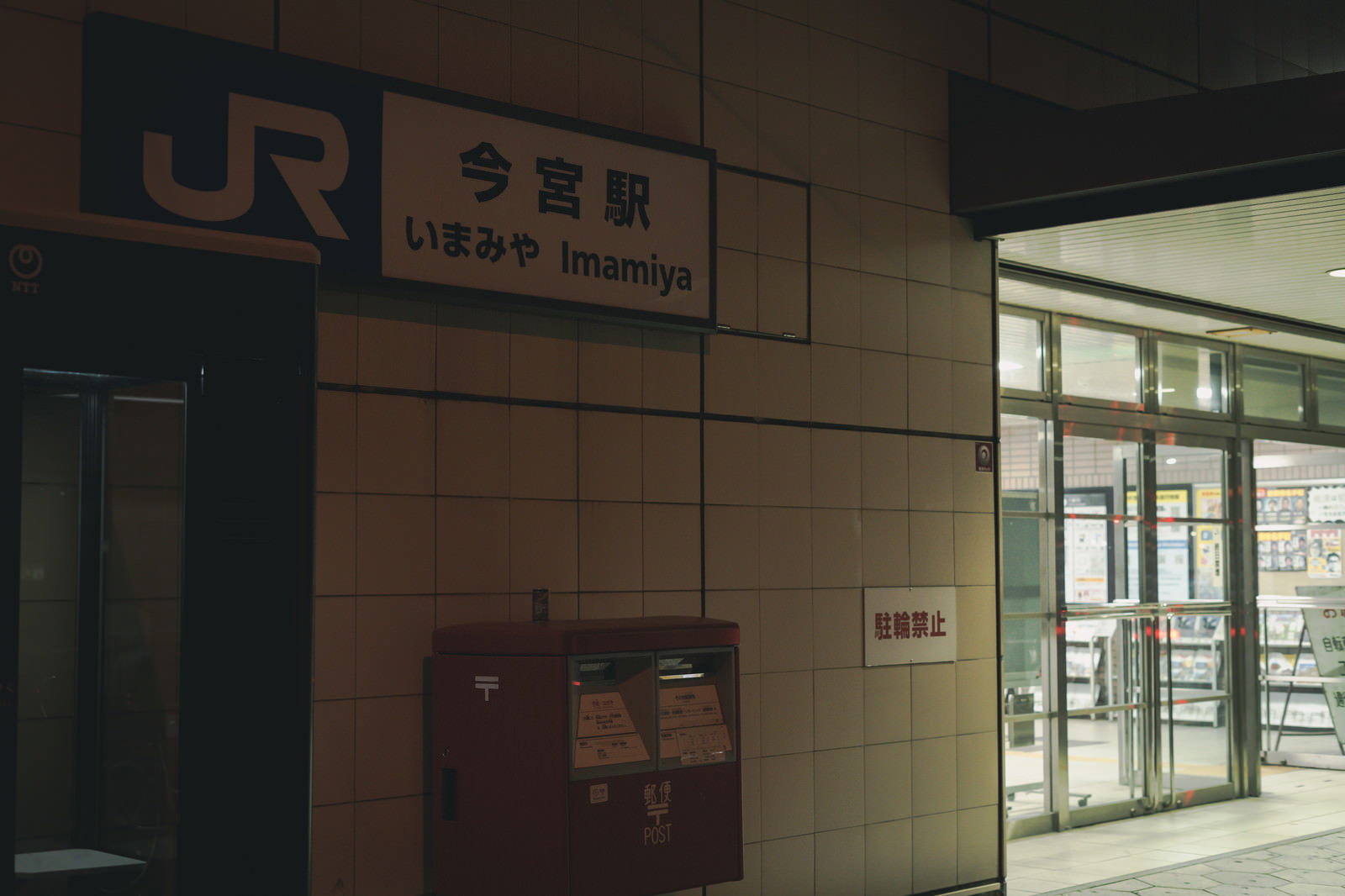 薄暗い今宮駅の外壁と赤いポスト