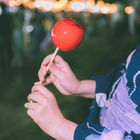 夏祭りの屋台で赤いりんご飴を握る浴衣姿の女性の手元の写真