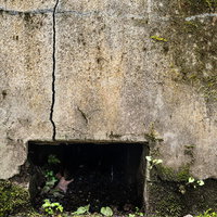 床下換気口と複数のひび割れが入ったコンクリート外壁の写真