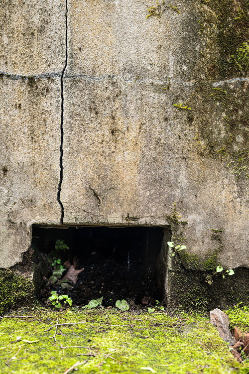 床下換気口と複数のひび割れが入ったコンクリート外壁