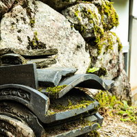石垣の前に積まれた苔むす古い瓦と歴史的な建築材料の写真