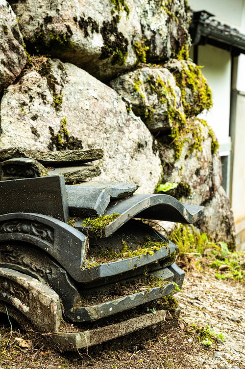 石垣の前に積まれた苔むす古い瓦と歴史的な建築材料