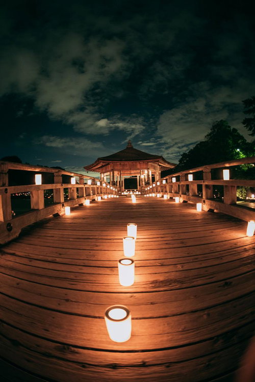 奈良の燈花会で夜間ライトアップされた木造橋と一列に並ぶろうそく