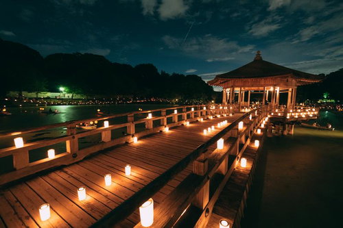 奈良の燈花会でろうそくの灯りに照らされた木造の橋と東屋