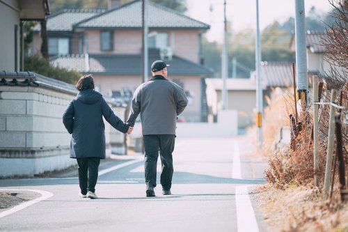 仲良く手を繋いで散歩する夫婦の午後、住宅地での日常の風景