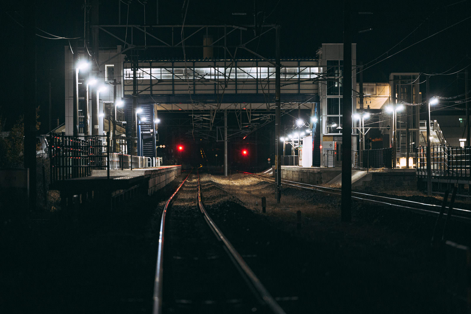夜の広野駅ホームと赤信号の点灯する線路の風景