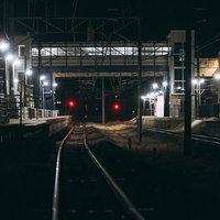 終電後の広野駅ホームと線路、赤信号が点灯する夜間の駅舎の写真