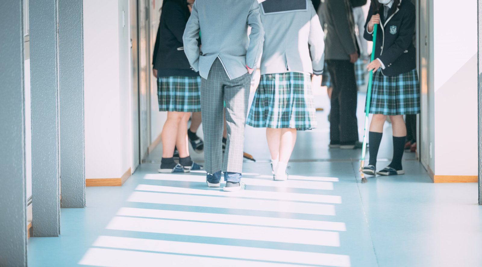 校舎の渡り廊下を移動する制服姿の高校生たち