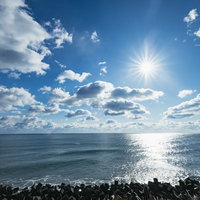 広野町の浜街道から見る太陽が照る海岸線と水平線の風景の写真