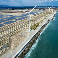 南相馬市鹿島区の海岸に並ぶ太陽光パネルと風力発電の写真