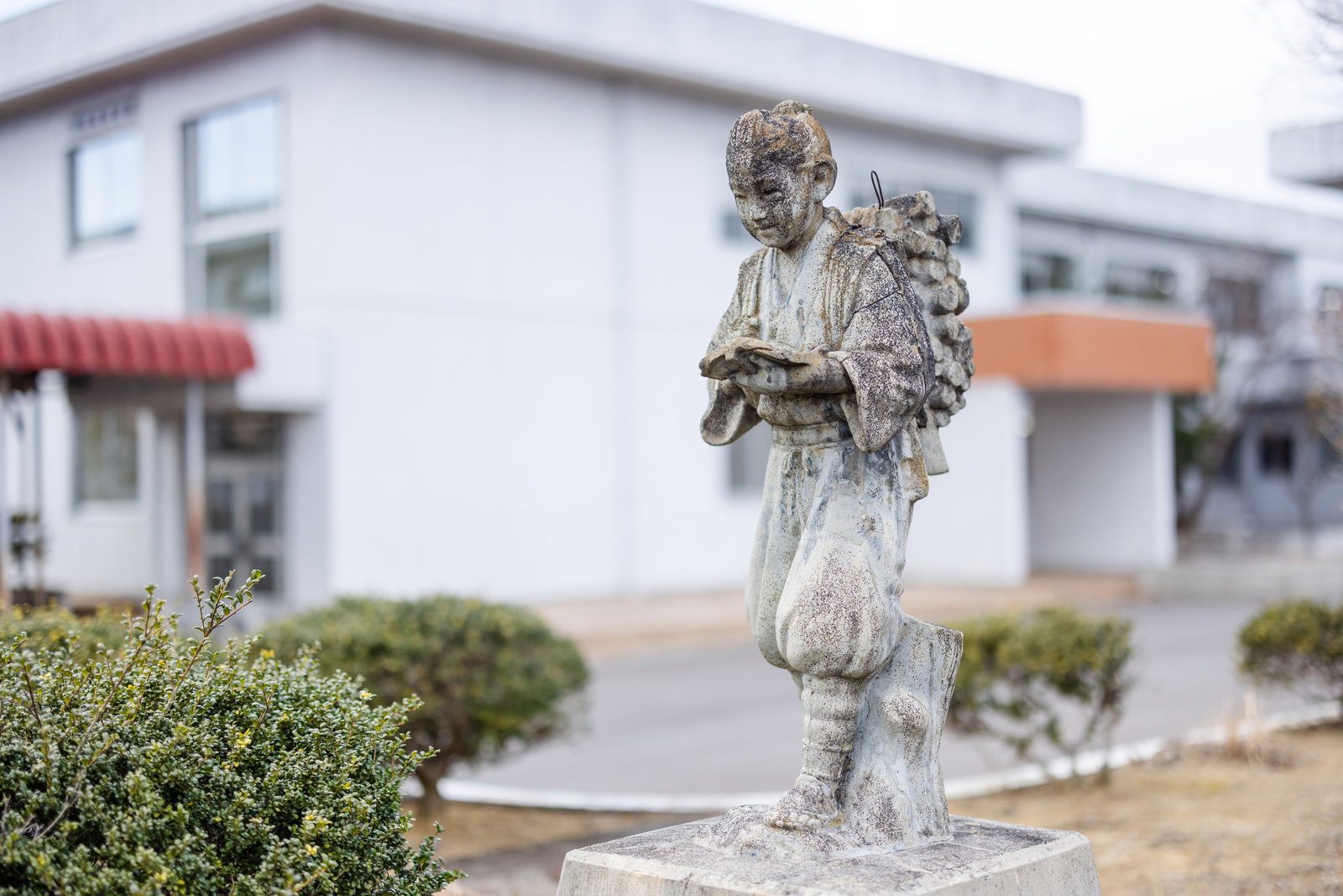 旧大野小学校跡地の古い石製の二宮金次郎像