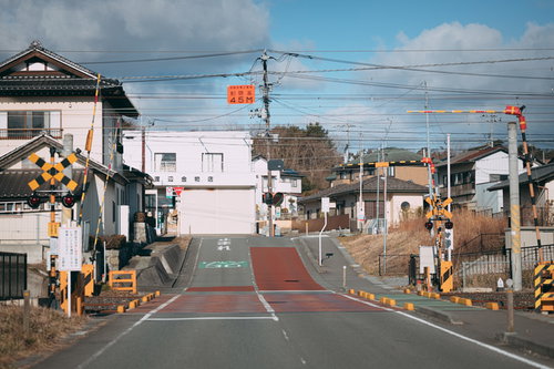 広野町駅の踏切を渡る線路と黄黒い警告灯の風景