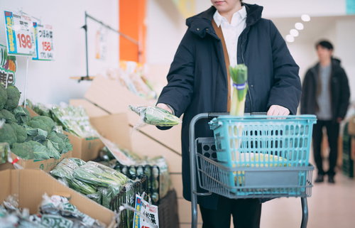 小高ストアで福島産の小松菜をショッピングカートに入れる買い物客