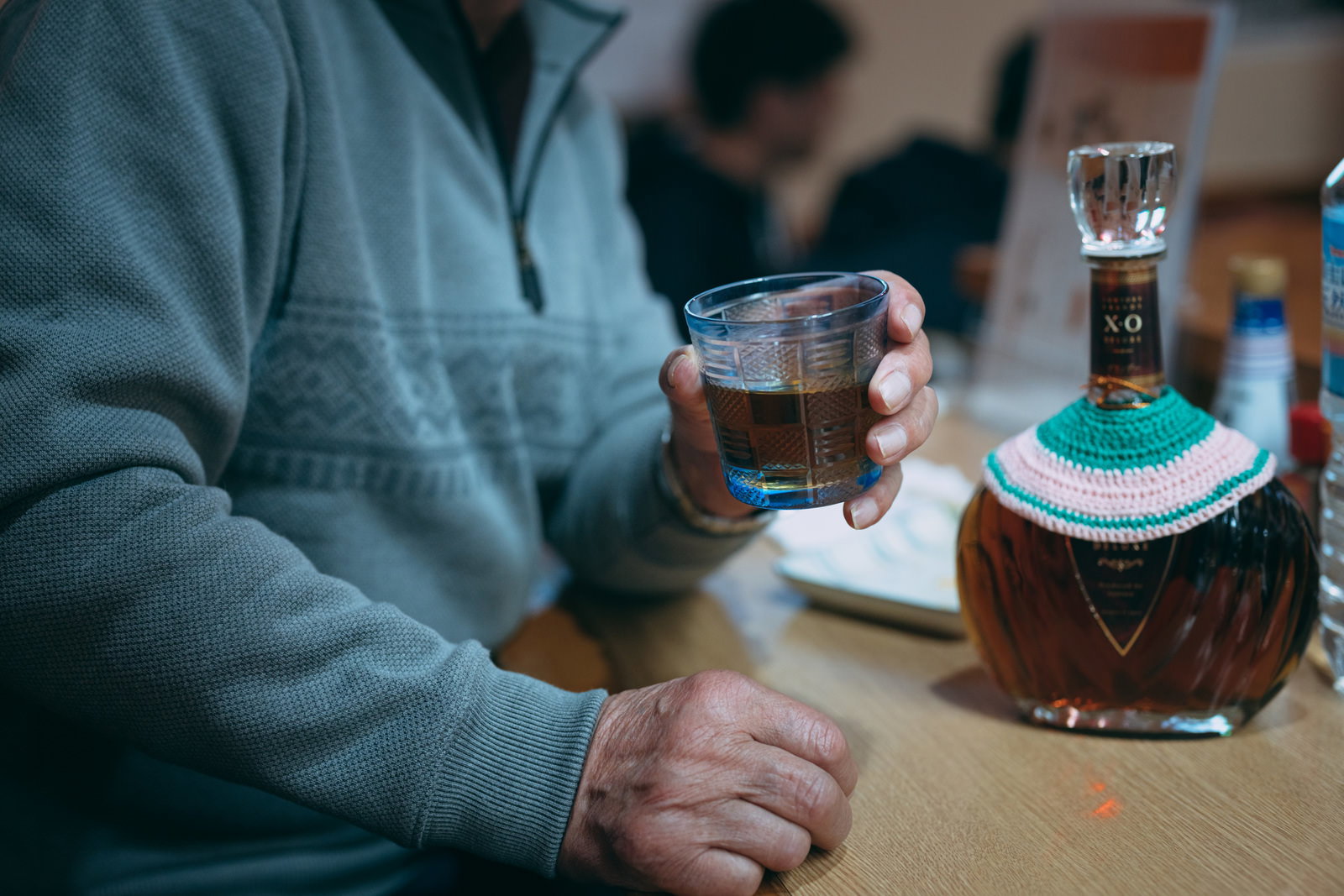 居酒屋でウイスキーのオンザロックをグラスで飲む人と、ボトルキープの瓶