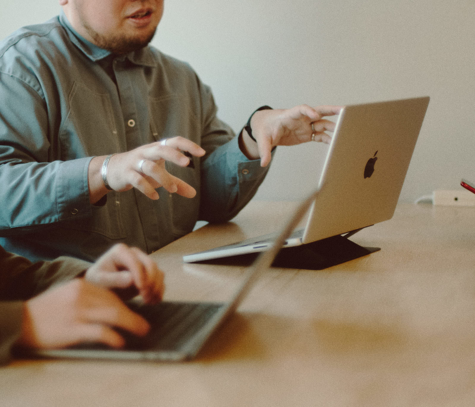 ノートパソコンを前にジェスチャーして説明する男性による対面会議の様子