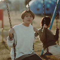 天神岬スポーツ公園のブランコで夕焼けを見つめる女性の写真