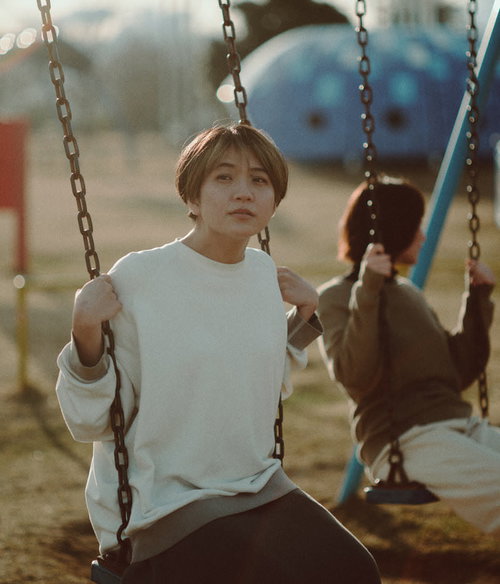 天神岬スポーツ公園のブランコで夕焼けを見つめる女性