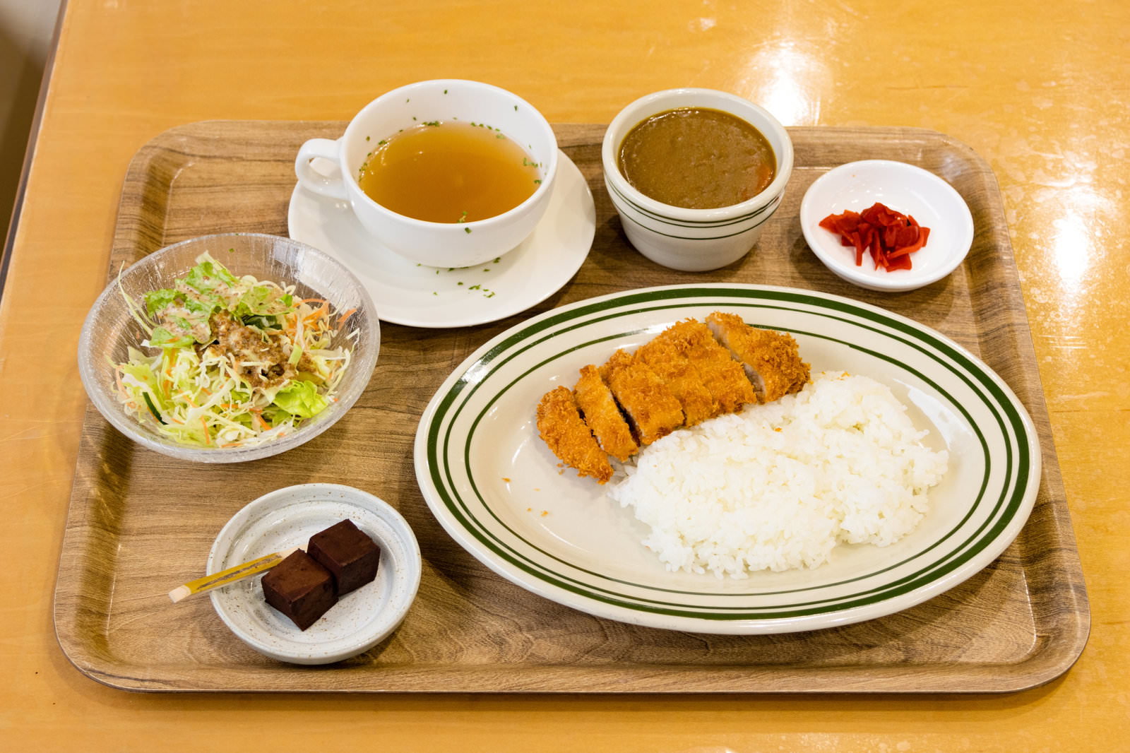木製トレーに盛られたカツカレー定食。揚げたてのとんかつとカレーライス、副菜が配置されている