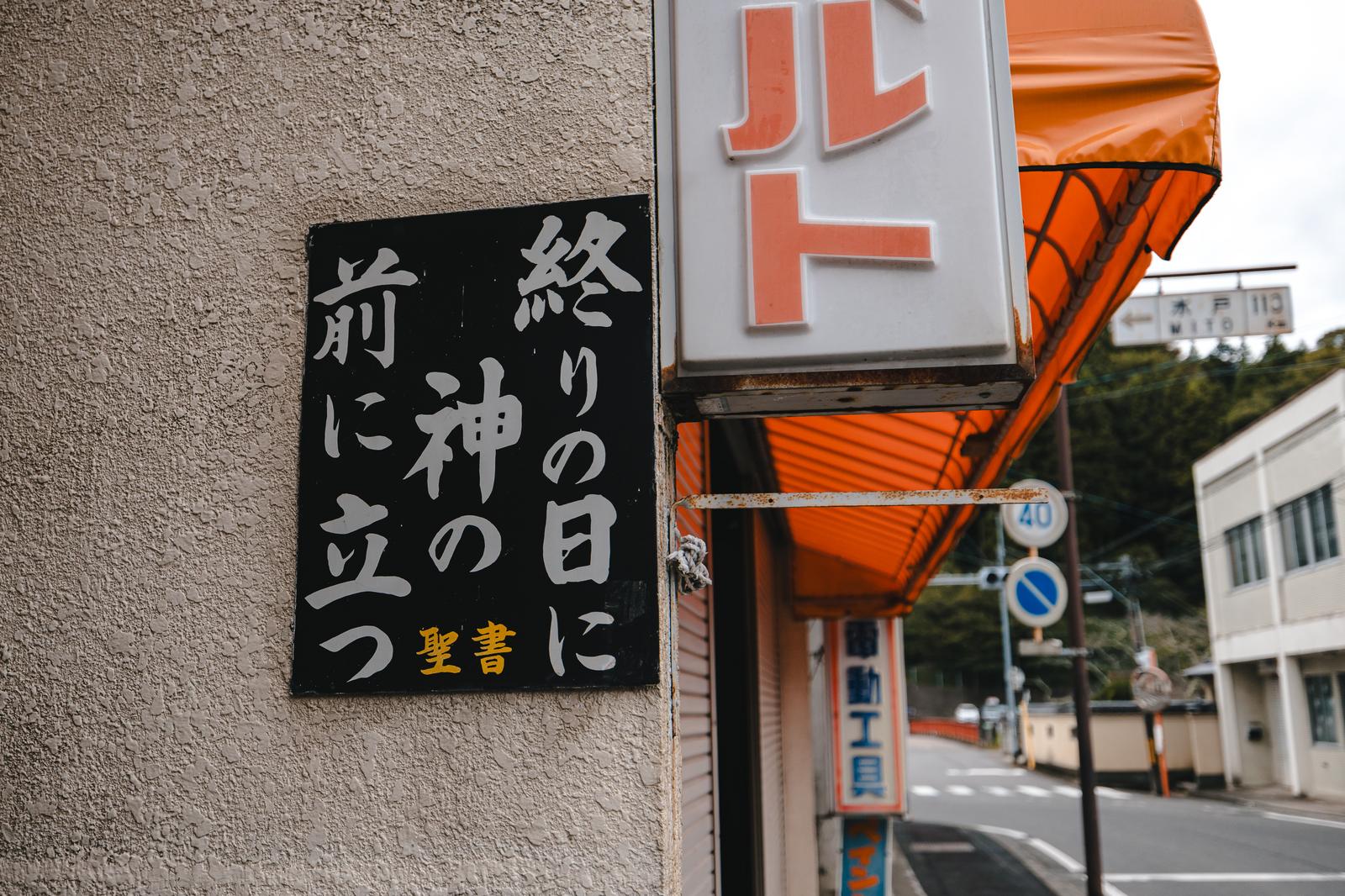 グレーの壁に黒い看板で聖書の文字が記された街角の写真
