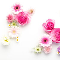 ホワイトボードの上に置かれたピンクと白の薔薇や小花のフレームの写真