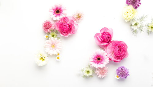 ホワイトボードの上に置かれたピンクと白の薔薇や小花のフレーム