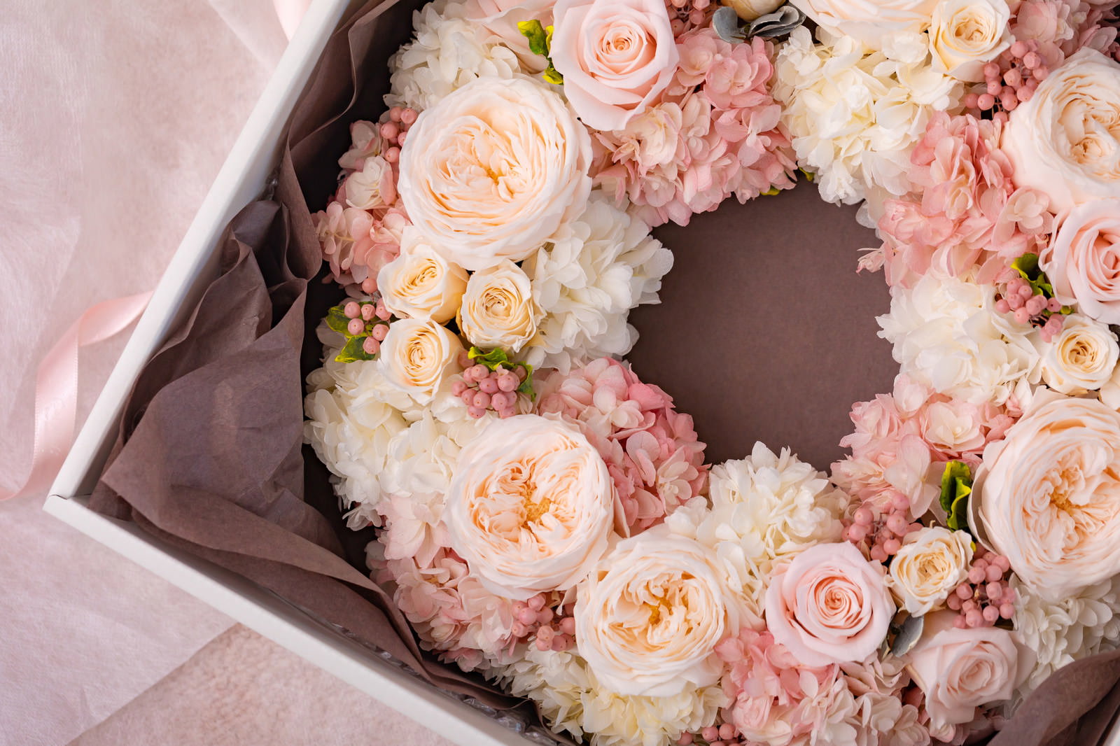 ピンク系の花で作られたプリザーブドフラワーのリースが箱に入っている