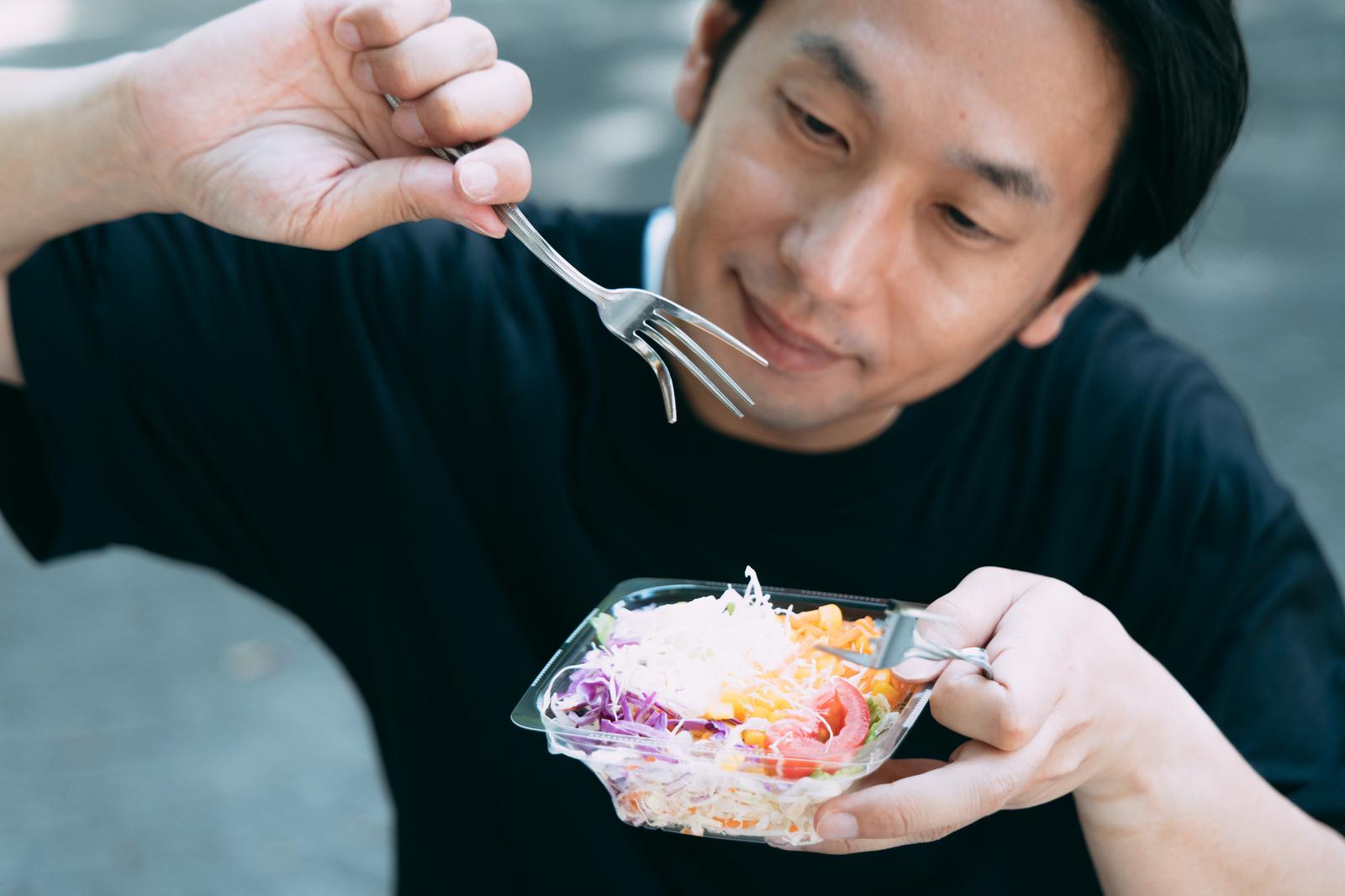 屋外でサラダを食べようとしている男性［モデル：大川竜弥］