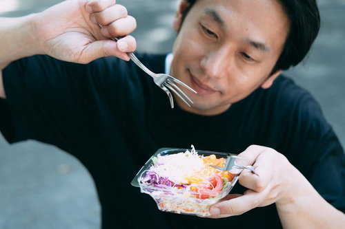 「サラダを食べる男性の写真」をAI生成したら、フォークがおかしな方向にむいて無機質な男性が生成されてしまった風