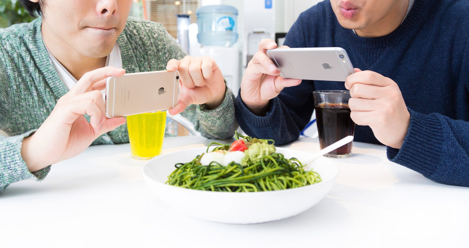 テーブルの料理をスマートフォンで撮影する2人の男性ブロガー［モデル：モデルリリース］