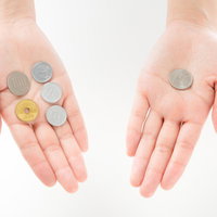 消費税の差額を手のひらで比べる硬貨の写真