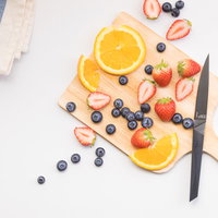 まな板に並ぶカット中のフルーツと包丁の写真