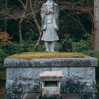 酬恩庵境内に立つ石像と秋の木々、歴史的な雰囲気の写真