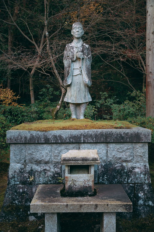 酬恩庵境内に立つ石像と秋の木々、歴史的な雰囲気
