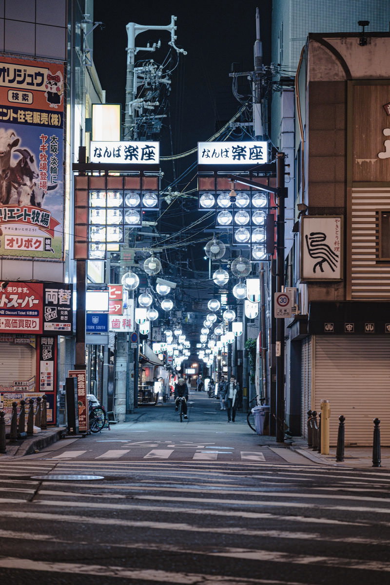 夜の難波繁華街で石段が続く路地裏にネオン看板が光る風景
