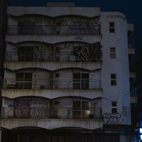 夜の難波の路地裏に建つ落書きされた雑居ビルの写真