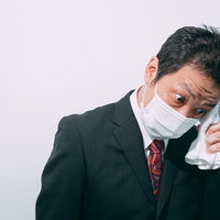 止まらない汗を拭く会社員の夏の熱中症対策の写真