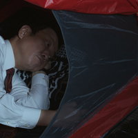 車内で仮眠をとる疲弊した営業マンの休息風景の写真