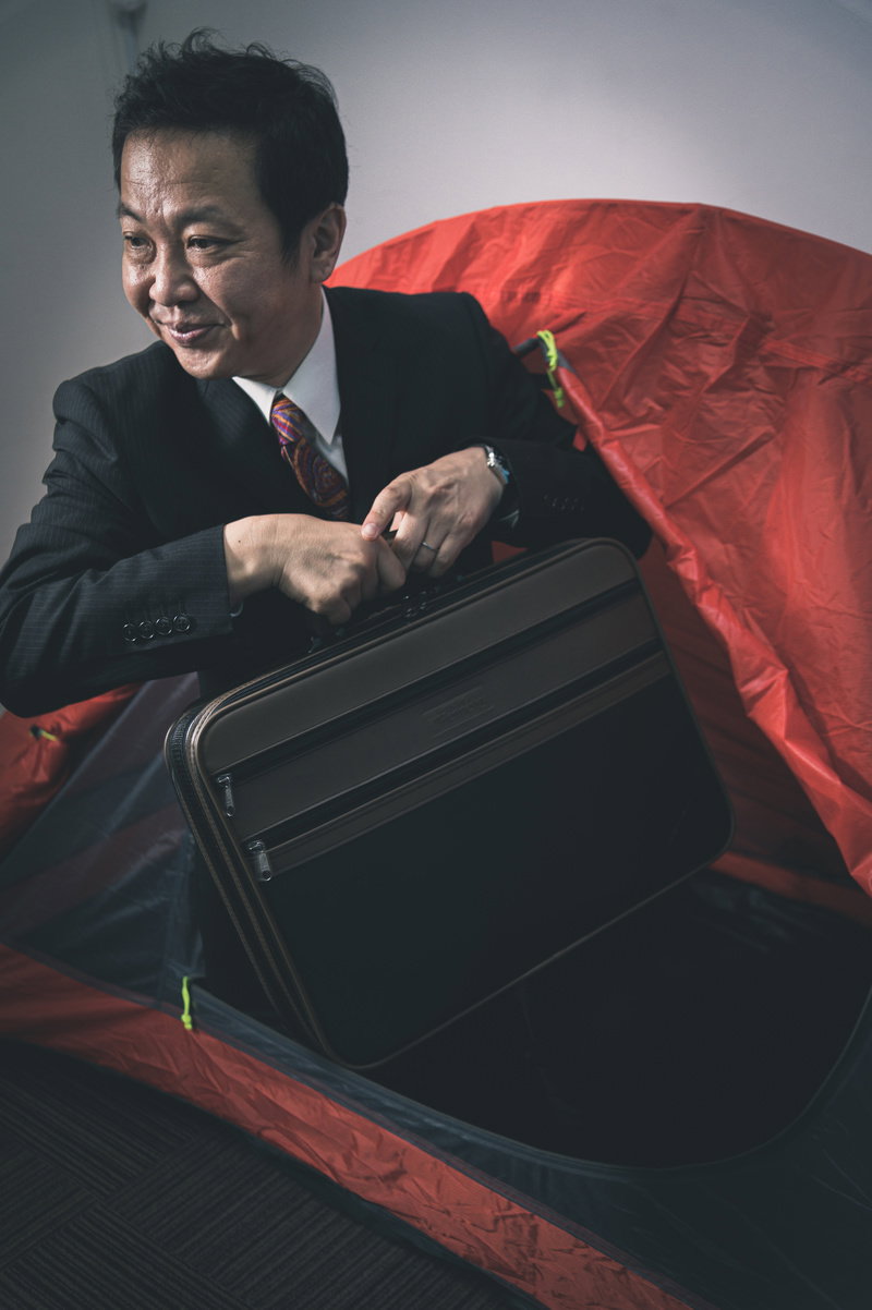 テント内でスーツケースを操作する営業マン［モデル：のせさん］