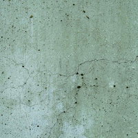 ひび割れが入った薄緑グレーのコンクリート壁のテクスチャーの写真
