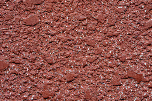 表面が欠けて劣化した赤茶色モルタル壁のテクスチャー