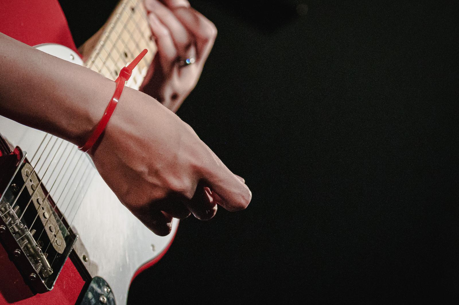 赤いギターを弾く結束バンドを付けたギタリスト