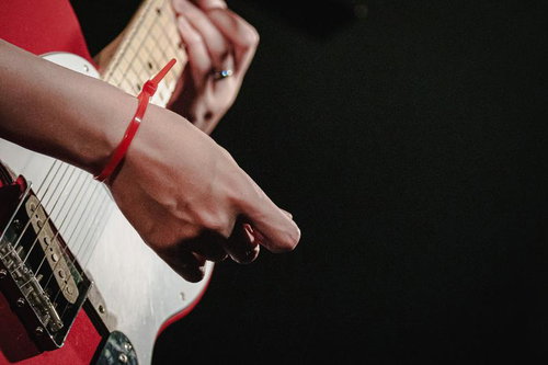 赤い結束バンドを付けて赤いストラトキャスターを弾くギタリスト