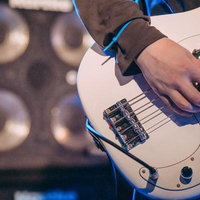 ライブステージで結束バンドを腕につけてベースを弾くベーシストの写真