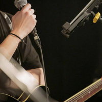 マイクを握りギターを弾くボーカルがステージで演奏の写真
