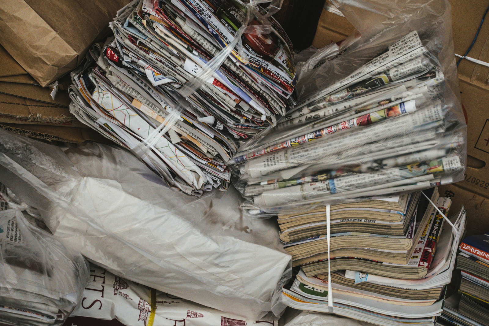 紐で束ねられた古い雑誌と新聞が積み重なっている様子