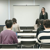 奇抜な登壇者がスクリーン前で登壇するセミナーの様子の写真