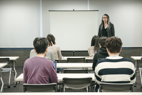 奇抜な登壇者がスクリーン前で登壇するセミナーの様子