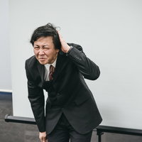 会議に遅刻して入ってきた部長が頭を下げて謝罪の写真