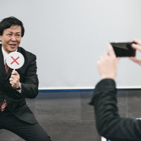 不正解ですぶっぶーと指摘するスーツ姿の男性の写真