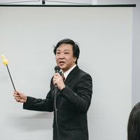 会議室でプレゼンテーションする上司、指示棒を持ちながら説明する場面の写真